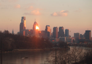 Philadelphia skyline from train, reflecting sun. 